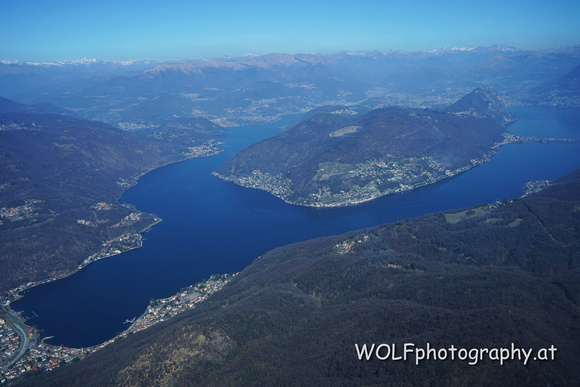 Luganer See von Süden: Rechts oben der Monte San Salvatore, zu dessen Füßen sich Lugano erstreckt. Im Bildhintergrund somit das Schweizer Tessin.
